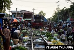 A train makes its way slowly past vendors as they remove their goods from the tracks at the railway bazaar near Tha Ye Zay railway station in Mandalay, Myanmar on May 19, 2019.