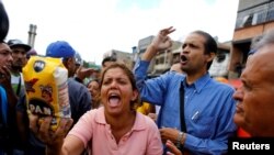 VENEZUELA – A woman shows a flour package outside a supermarket as they shout slogans over food shortage in Caracas, Venezuela, June 11, 2016.