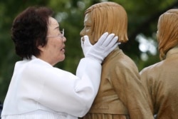 Lee Yong-soo, who was forced to serve for the Japanese troops as a sex slave during World War II, touches the face of a statue of a girl symbolizing the issue of wartime "comfort women" during its unveiling ceremony in Seoul, South Korea on August 14, 2019. Ahn Young-joon/AP