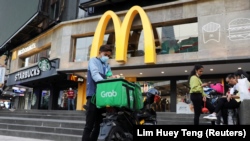 A GrabFood rider gets ready for a delivery outside a McDonald?s restaurant, amid the coronavirus disease (COVID-19) outbreak in Kuala Lumpur, Malaysia July 8, 2020.