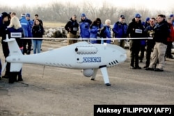 OSCE members for its Special Monitoring Mission stand around a UAV employed in Ukraine.