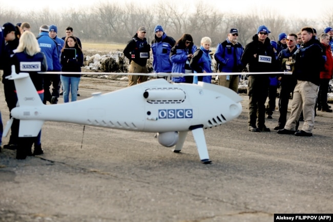 OSCE members for its Special Monitoring Mission stand around a UAV employed in Ukraine.