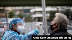 FILE PHOTO: A healthcare worker in personal protective equipment (PPE) takes a swab from a man for a rapid antigen test at a drive-through testing site, during the coronavirus disease (COVID-19) pandemic, in Athens, Greece, Dec. 18, 2020. 