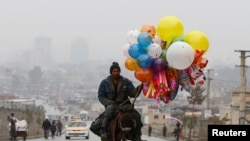 Afghanistan -- An Afghan man rides on his donkey, holding balloons for sale during Norouz Day celebrations, a festival marking their spring and new year, in Kabul, March 21, 2017