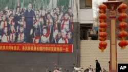 Residents walk past a propaganda board showing Chinese President Xi Jinping with local children and slogans calling for unity amongst the different ethnicities in Shule county in Xinjiang Uyghur Autonomous Region on March 20, 2021. (Ng Han Guan/AP)