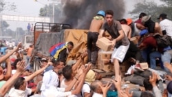 VENEZUELA – People try to take part of the humanitarian aid from a truck that was set on fire in Ureña, Venezuela, on 23 February 2019.