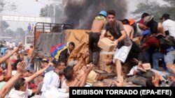 VENEZUELA – People try to take part of the humanitarian aid from a truck that was set on fire in Ureña, on 23 February 2019.