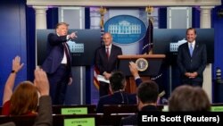 U.S. President Donald Trump gestures towards media members who raise their hands to ask questions while Health and Human Services (HHS) Secretary Alex Azar and Commissioner of Food and Drug Administration Dr. Stephen M. Hahn look on during a news conference.
