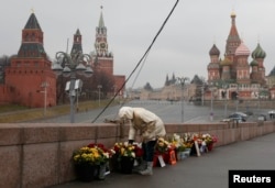Russia -- A woman adjusts flowers at the site of the assassination of Kremlin critic Boris Nemtsov in central Moscow, March 20, 2017