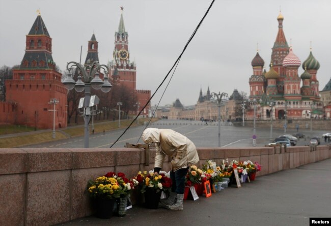Russia -- A woman adjusts flowers at the site of the assassination of Kremlin critic Boris Nemtsov in central Moscow, March 20, 2017