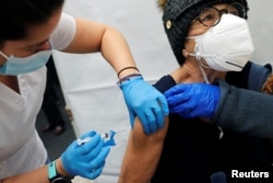 A healthcare worker administers a shot of the Moderna COVID-19 Vaccine to a woman at a pop-up vaccination site operated by SOMOS Community Care during the coronavirus disease (COVID-19) pandemic in Manhattan in New York City, New York, U.S., January 29, 2021. (REUTERS/Mike Segar)