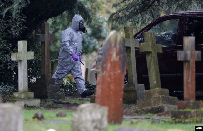 A man in a hazmat suit walks by London Road Cemetery in Salisbury, England, near the home of Sergei Skripal, who, along with his daughter Yulia were poisoned with Novichok on March 4, 2018.