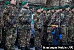 LITHUANIA -- A boy stands near Lithuanian soldiers during a celebration of Independence day at Independence Square, in front of the Parliament Palace in Vilnius, March 11, 2019