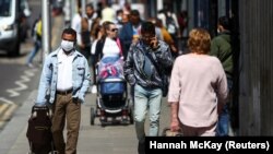 People walk down a street following the coronavirus disease (COVID-19) outbreak, in Ilford, London, Britain July 29, 2020.
