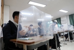 South Korean students sit behind protective shields as a preventative measure against the COVID-19 novel coronavirus in a classroom in Daejeon on May 20, 2020.
