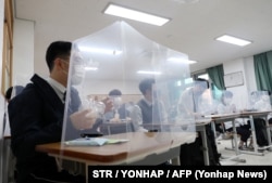South Korean students sit behind protective shields as a preventative measure against the COVID-19 novel coronavirus in a classroom in Daejeon on May 20, 2020.