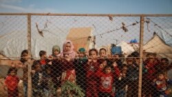 Displaced Syrian children stand behind a fence outside their tents a camp set up in Idlib's northern countryside near the Syria-Turkey border, October 22, 2019. (Aaref Watad/AFP)