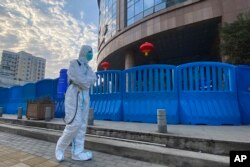 A worker in protective clothing carrying disinfecting equipment walks outside Wuhan Central Hospital. This photo was taken on February 6, 2021, in Wuhan.