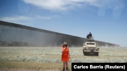 A White House staff member watches President Donald Trump's motorcade arrive to tour a recently constructed section of the the U.S.-Mexico border wall in San Luis, Arizona, U.S., June 23, 2020.