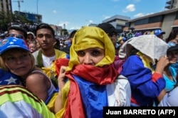 Venezuela -- An opposition supporter has a Venezuelan national flag wrapped around her head as she listens to Venezuelan opposition leader Juan Guaido during a gathering in Caracas on February 2, 2019. - Tens of thousands of protesters poured onto the streets
