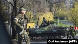 Pro-Russian separatist soldiers stand next to a vehicle as they close off a road in Donetsk