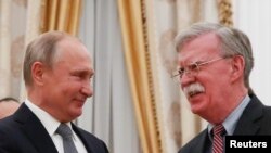 Russia -- Russian President Vladimir Putin (L) shakes hands with U.S. National Security Adviser John Bolton during Bolton's visit to the region, October 23, 2018.