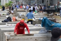 Ecuador -- People construct burial vaults in the Angela Maria Canalis cemetery.