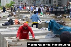Ecuador -- People construct burial vaults in the Angela Maria Canalis cemetery.