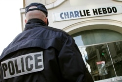 A policeman stands guard outside the French satirical weekly Charlie Hebdo in Paris, Feb. 9, 2006, after the publication reprinted cartoons of the Prophet Muhammad and published one of its own on its front page.