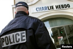 A policeman stands guard outside the French satirical weekly Charlie Hebdo in Paris, Feb. 9, 2006, after the publication reprinted cartoons of the Prophet Muhammad and published one of its own on its front page.