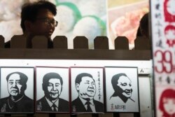 A man stands near a series of paper cuttings depicting Chinese President Xi Jinping next to former Chinese leader Mao Zedong and Deng Xiaoping. This photo was taken on March 1, 2018, in Shanghai.