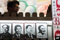 A man stands near a series of paper cuttings depicting Chinese President Xi Jinping next to former Chinese leader Mao Zedong and Deng Xiaoping. This photo was taken on March 1, 2018, in Shanghai.
