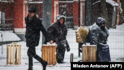 RUSSIA -- Women beg for money in front of an Orthodox church as it snows in Moscow, January 30, 2018