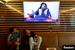 Iraqi youth watch the news of Islamic State leader Abu Bakr al-Baghdadi's death