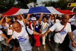Supporters of Thailand’s Prime Minister Prayut Chan-o-cha walk with a Thai national flag as they support their support for the government at a park in Bangkok, Thailand January 12, 2020.