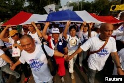 Supporters of Thailand’s Prime Minister Prayut Chan-o-cha walk with a Thai national flag as they support their support for the government at a park in Bangkok, Thailand January 12, 2020.