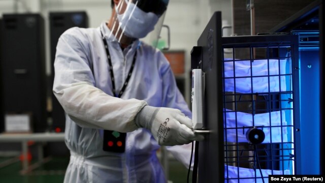 A worker in protective suit shows a UVC sterilizer unit for medical staff, during the COVID-19 outbreak, at a factory in Samutprakarn, Thailand April 15, 2020.