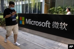 A man looks at his smartphone as he walks by the Microsoft office in Beijing on August 7, 2020. (AP)