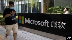 A man looks at his smartphone as he walks by the Microsoft office in Beijing on August 7, 2020. The Biden administration on Monday, July 19, 2021, blamed China for a hack of Microsoft Exchange email server software that compromised tens of thousands of computers worldwide.