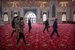 Officials accompany foreign journalists during a visit to the Xinjiang Islamic Institute in Urumqi on April 22, 2021. (AP Photo/Mark Schiefelbein)