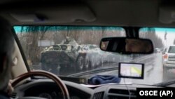 In this European monitoring mission photo in the eastern city of Luhansk, personnel carriers and armed men drive in the city center, November 21, 2017. (OSCE SMM/AP)