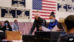 Two women, wearing protective masks due to the COVID-19 pandemic, cast their ballots at a polling station at Windham, N.H. High School in Windham, New Hampshire, on November 3, 2020. (Charles Krupa/AP)