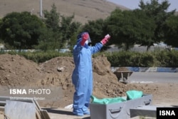 Iran --A cemetery worker preforms an Islamic prayer over the body of a COVID-19 victim.