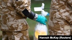 Britain -- People in military hazardous material protective suits collect an item in Queen Elizabeth Gardens in Salisbury, Britain, July 19, 2018. 
