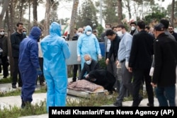Virus Outbreak Mideast Iran -- Relatives mourn over the body of Fatemeh Rahbar, a lawmaker-elect from a Tehran constituency, who died on Saturday after being infected with the new coronavirus, at Behesht-e-Zahra cemetery, just outside Tehran, Iran, Sunday