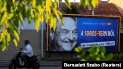 HUNGARY -- FILE PHOTO: A man rides his moped past a government billboard displaying George Soros amid accusations he was trying to bring in immigrants.