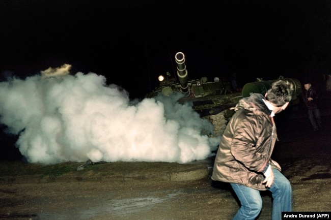 A Lithuanian demonstrator runs in front of a Soviet Red Army tank