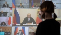 RUSSIA -- A woman watches the online meeting of Russian President Vladimir Putin with the heads of Russia's regional governments in Domodedovo, Moscow region, April 28, 2020