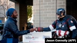 US -- Matt Gnojek, a.k.a. Colorado Captain, hands out stickers to a voter in Denver, Colorado on November 6, 2018.