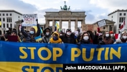 Demonstrators display a banner in the colors of the Ukrainian flag during a protest at Berlin's Brandenburg Gate on January 30, 2022. (John MACDOUGALL / AFP) 